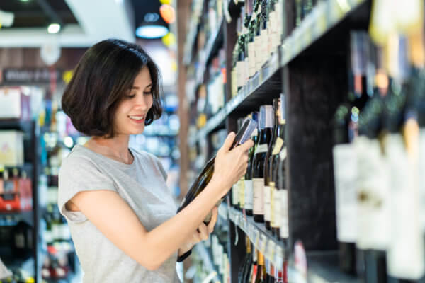 woman looking at wine bottle in supermarket